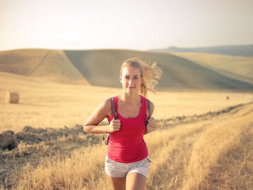 A woman jogging through vast, golden wheat fields under the summer sun, symbolizing freedom and adventure.