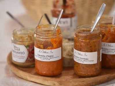A selection of Hungarian vegetable spreads in jars on a wooden tray.